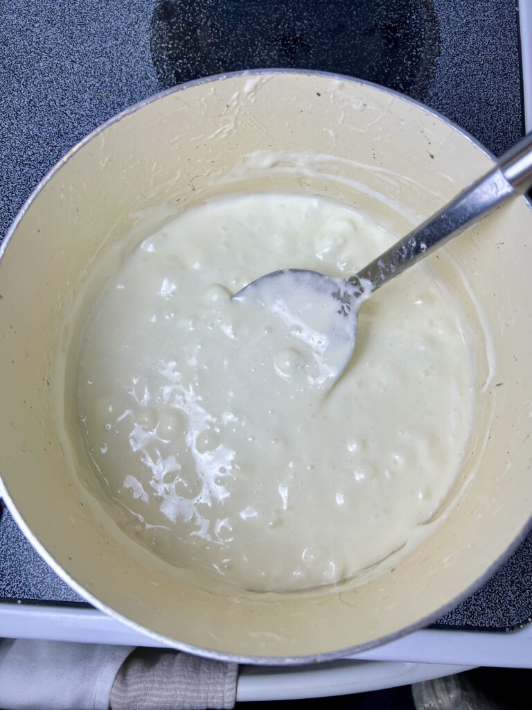 Smooth melted marshmallow and butter mixture in a pot, ready to be mixed with Rice Krispies for Christmas wreath treats.