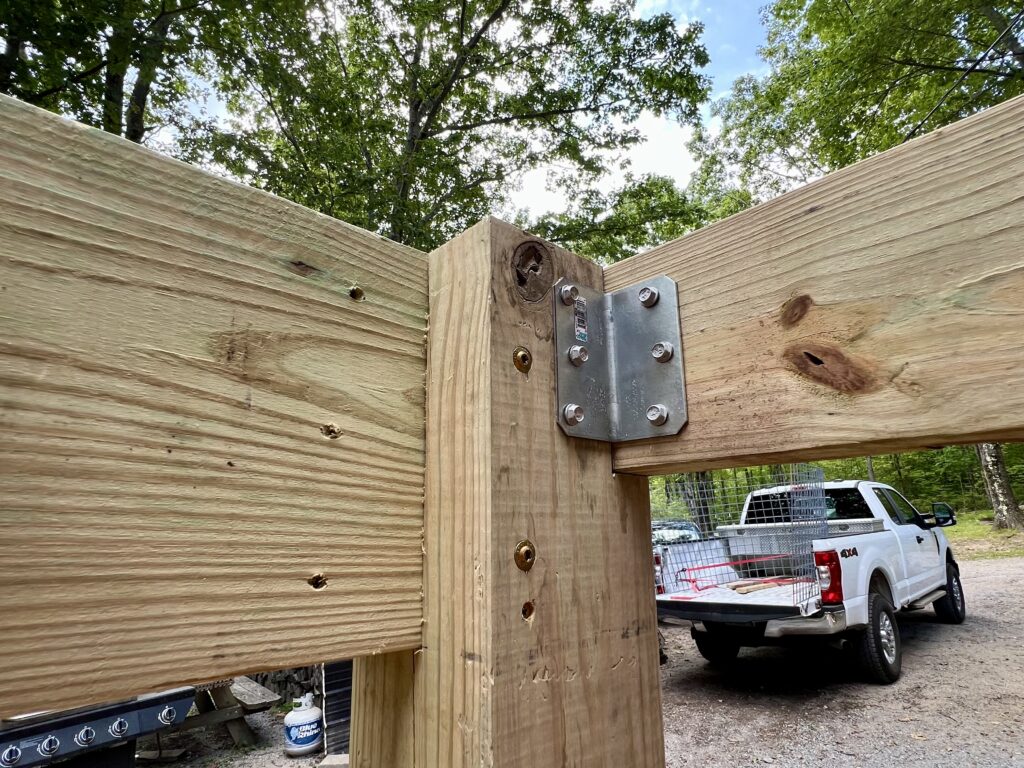 Deck beam attached to vertical post using galvanized brackets during DIY deck construction