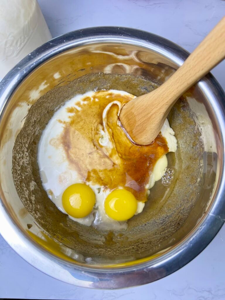 Eggs, sourdough discard, and vanilla being mixed into brown butter for sourdough chocolate chip cookies