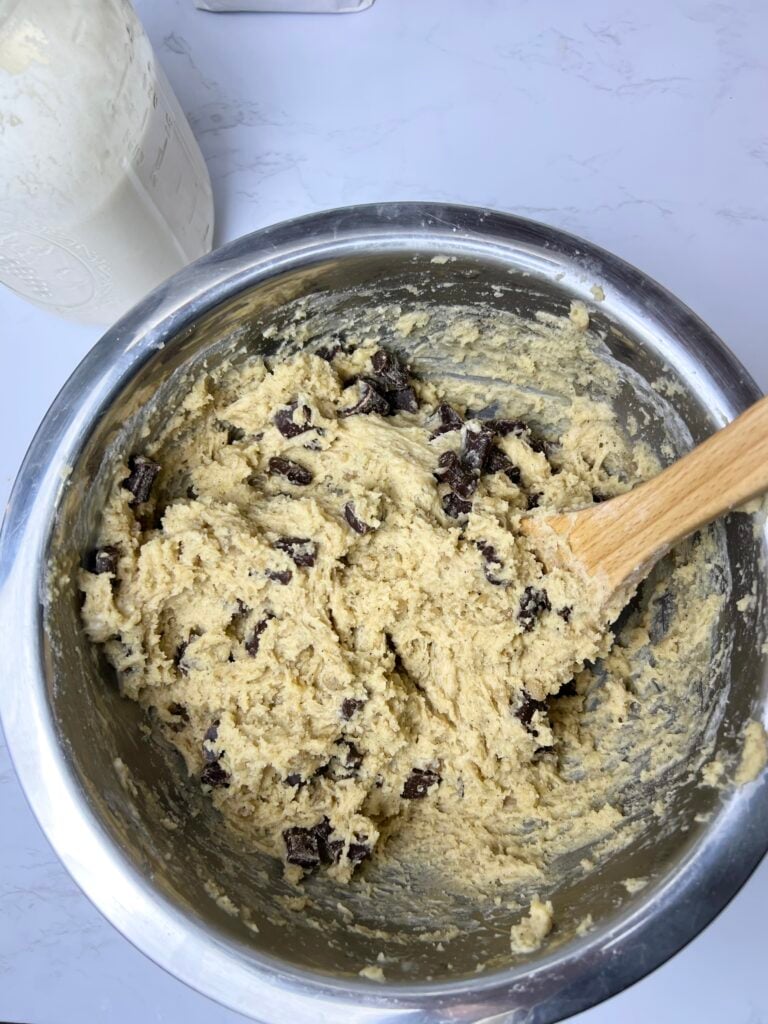 Brown butter sourdough chocolate chip cookie dough mixed in a bowl with chunks of chocolate