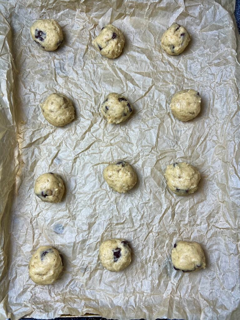 Brown butter sourdough chocolate chip cookie dough scooped into balls and arranged on parchment paper before baking