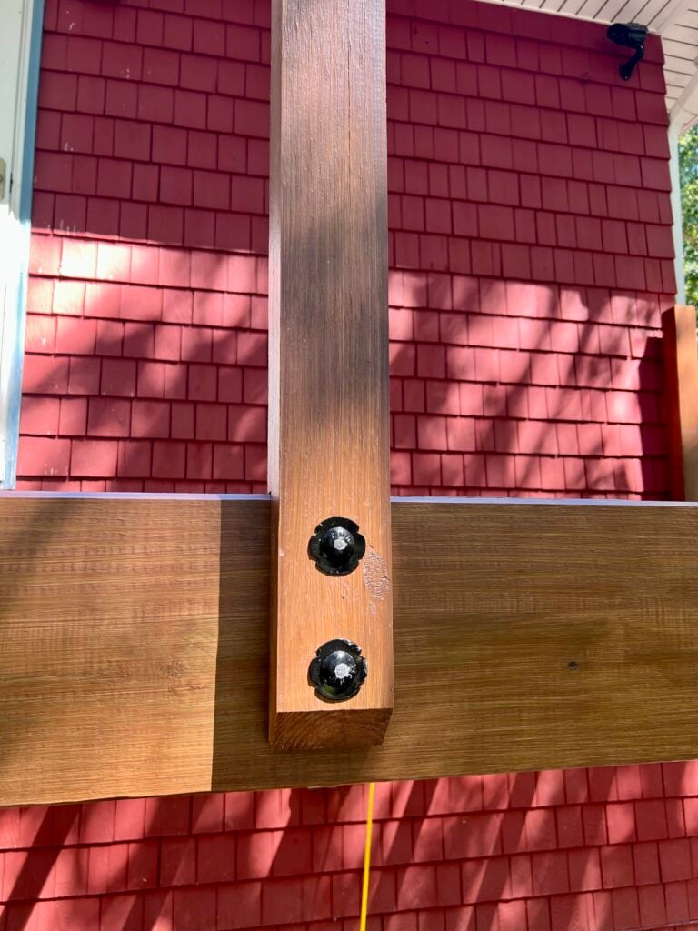 Close-up of deck post secured to beam with carriage bolts in DIY deck build