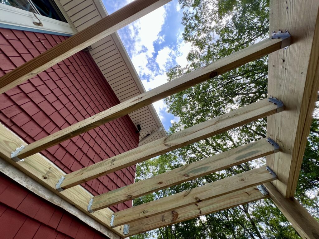 Underside view of deck framing showing joist hangers and Trex deck structure