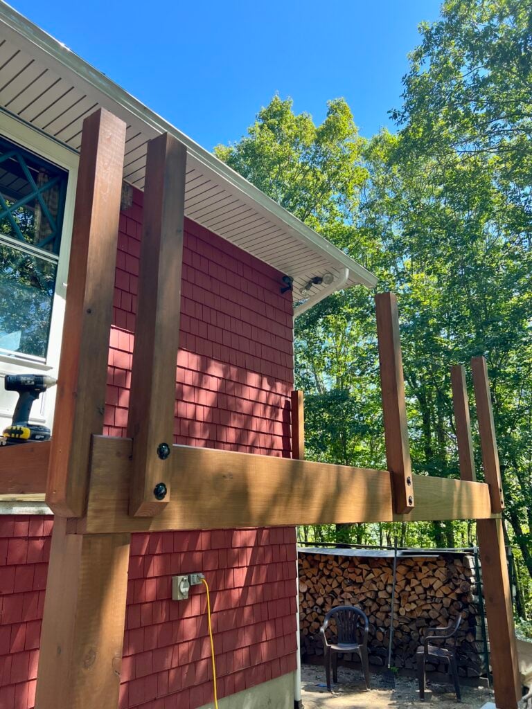 Side view of deck posts bolted to beam during DIY deck construction