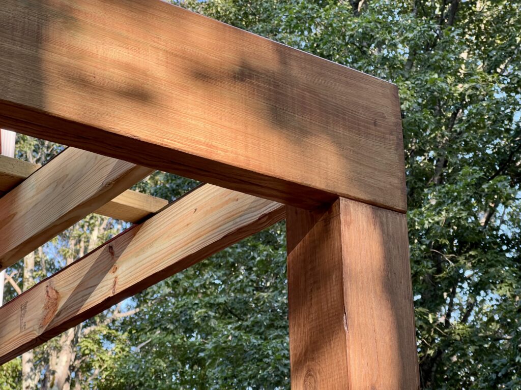 Side view of stained deck beam with joists installed on DIY deck project
