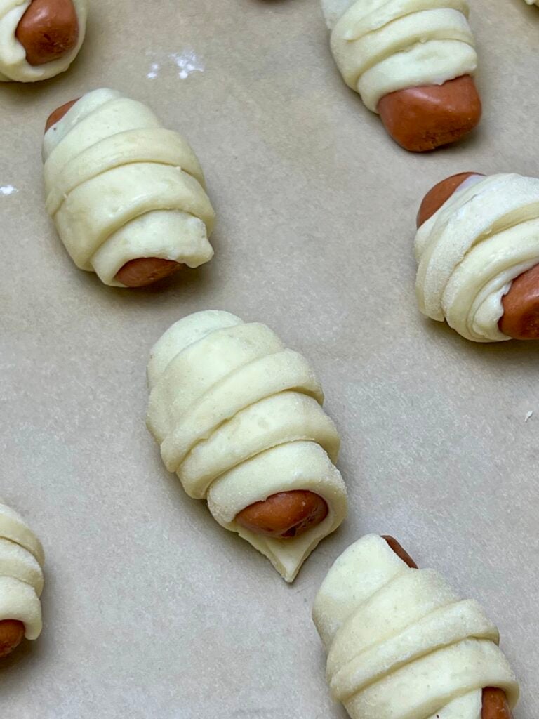 these are wrapped pigs in a blanket on a parchment lined baking sheet ready to go into the oven. 