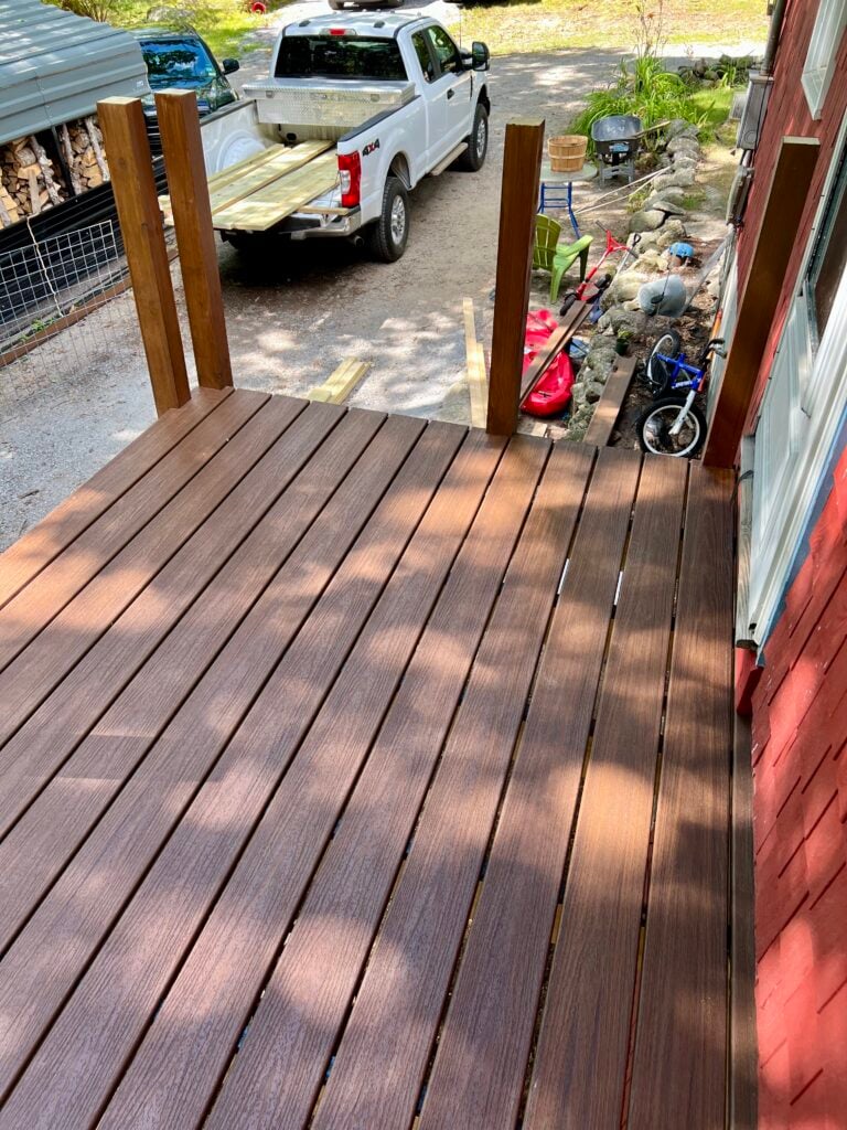 Trex composite deck boards installed along house exterior during DIY deck build