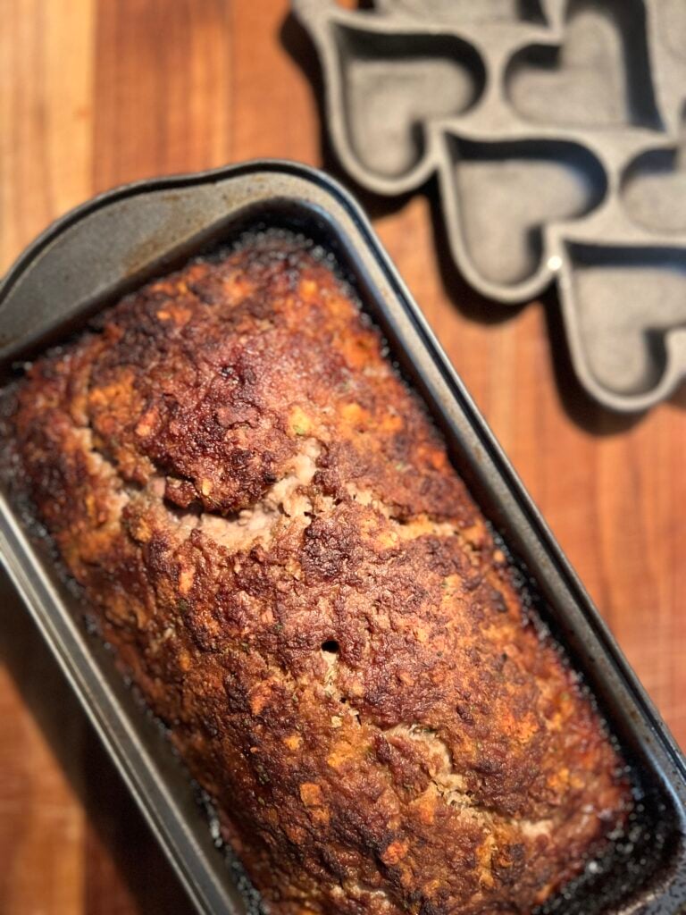 Fully baked homemade meatloaf with a caramelized BBQ sauce topping in a loaf pan, made using an easy meatloaf recipe with few ingredients.