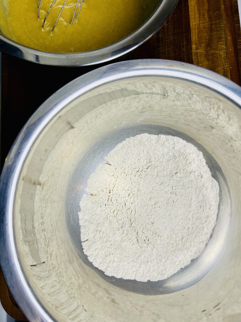 Dry ingredients for oatmeal raisin cookies measured in a metal bowl, including flour, cinnamon, baking soda, and salt