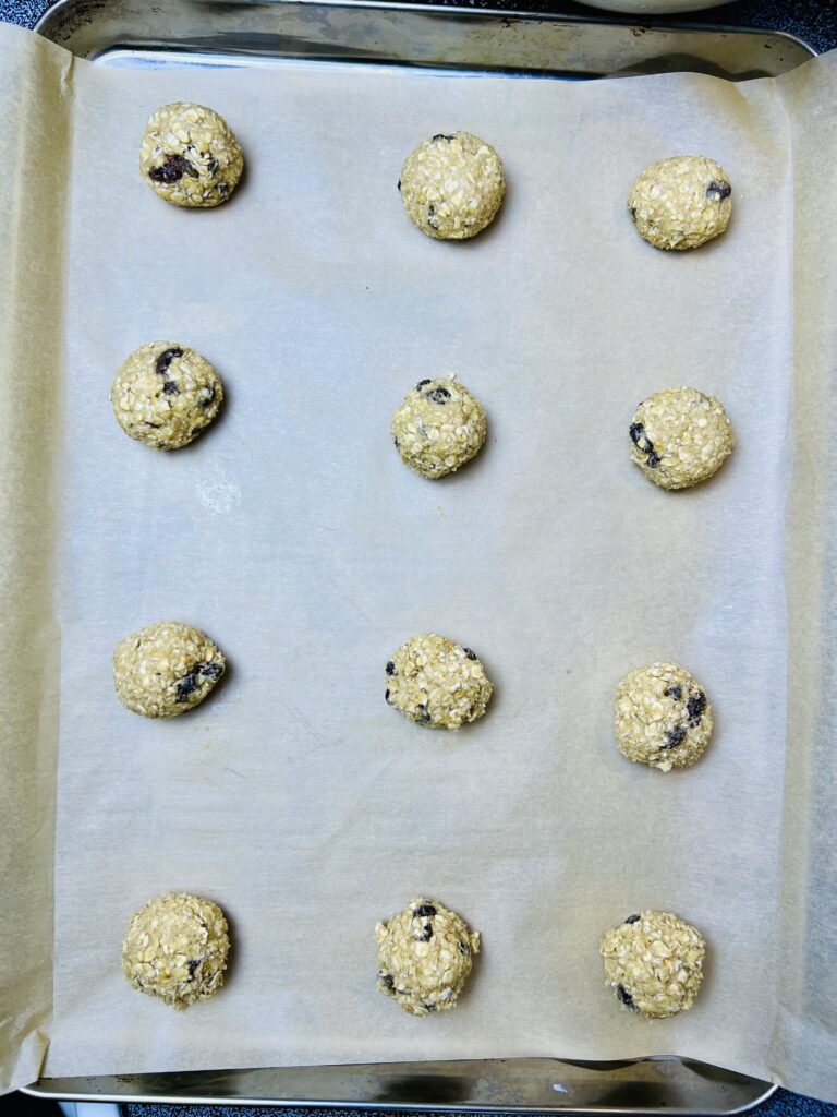 Oatmeal raisin cookie dough scooped into round balls and spaced evenly on a parchment lined baking sheet