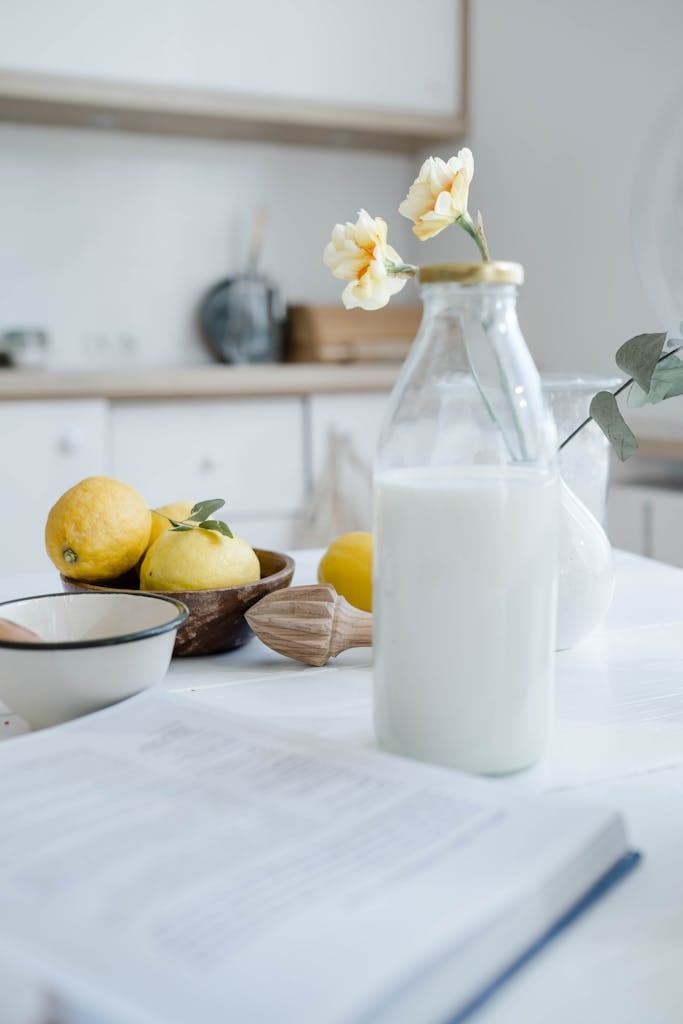A serene kitchen scene featuring lemons, milk, and flowers.