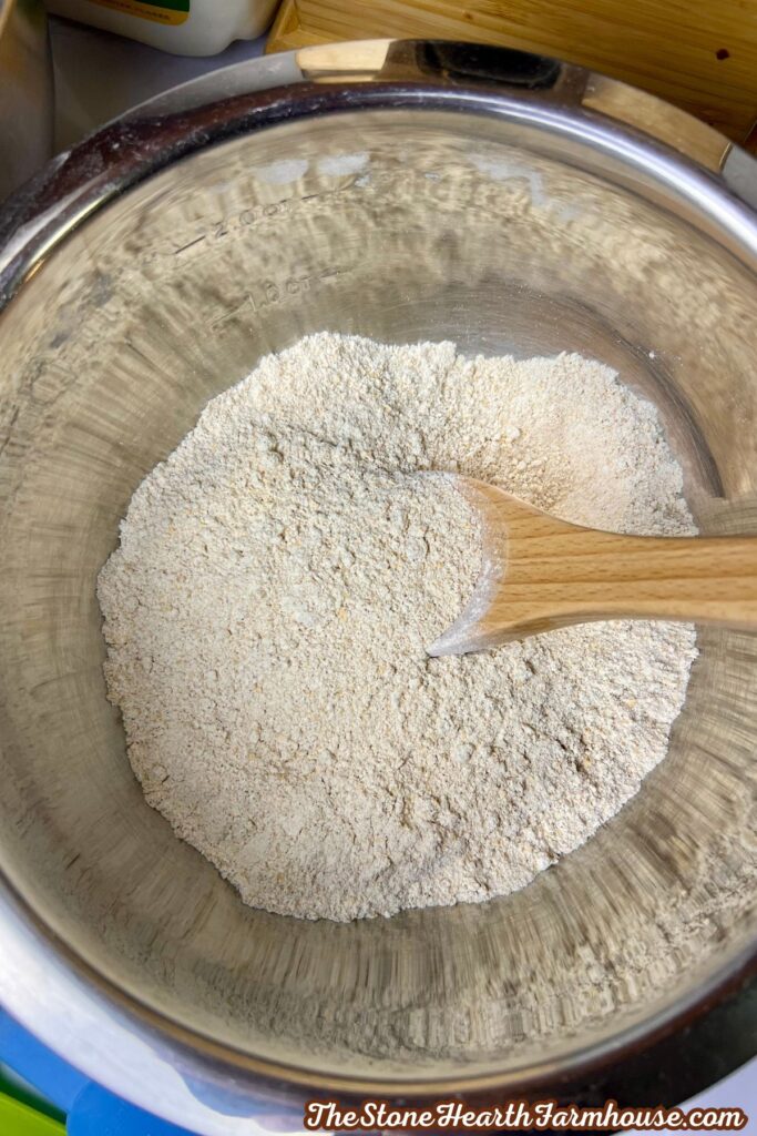 Freshly milled soft white wheat flour in a mixing bowl with a wooden spoon