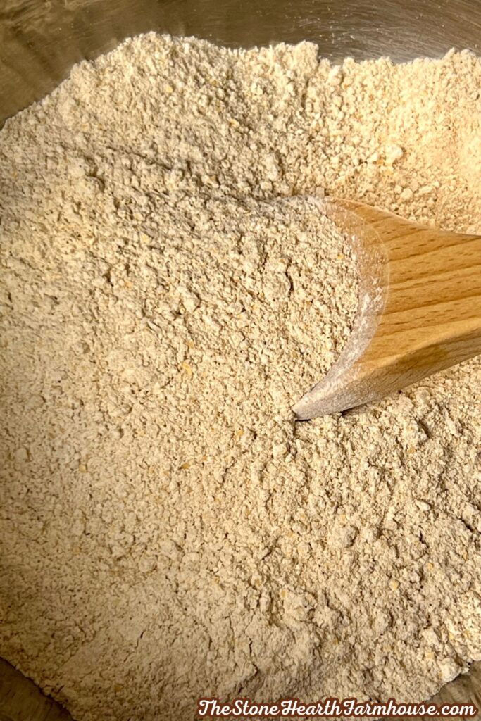 Freshly milled soft white wheat flour being mixed in a bowl with a wooden spoon