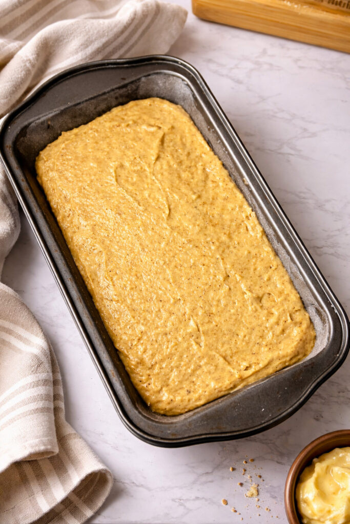 Fresh milled banana bread batter spread into a loaf pan before baking, made with soft white wheat flour and ripe bananas