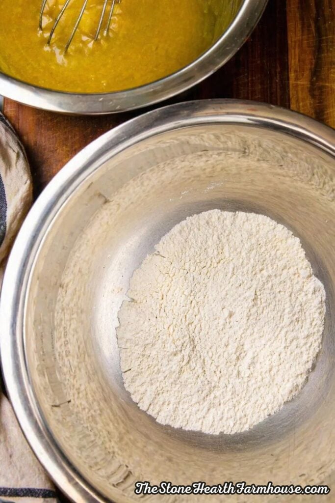 Dry ingredients for oatmeal raisin cookies measured in a metal bowl, including flour, cinnamon, baking soda, and salt