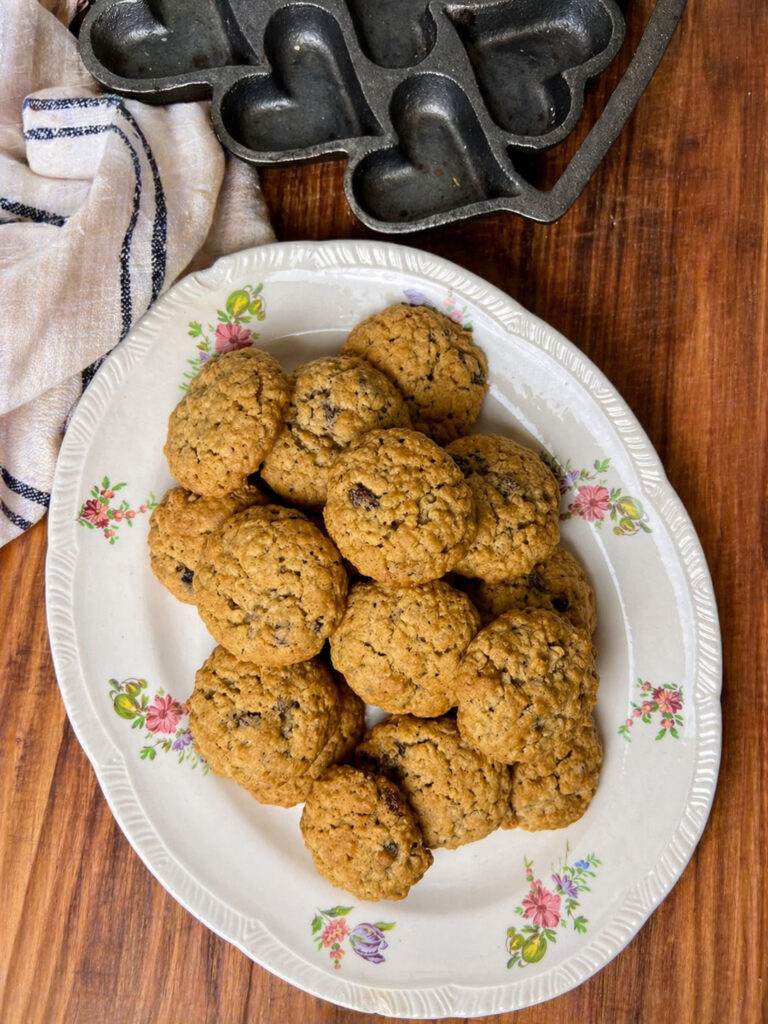 Plate of freshly baked oatmeal raisin cookies arranged on a vintage floral dish on a wooden countertop