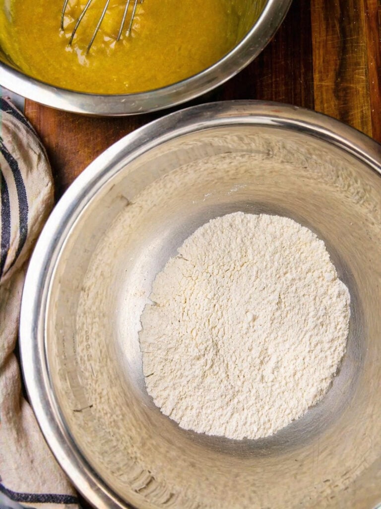 Dry ingredients for oatmeal raisin cookies measured in a metal bowl, including flour, cinnamon, baking soda, and salt