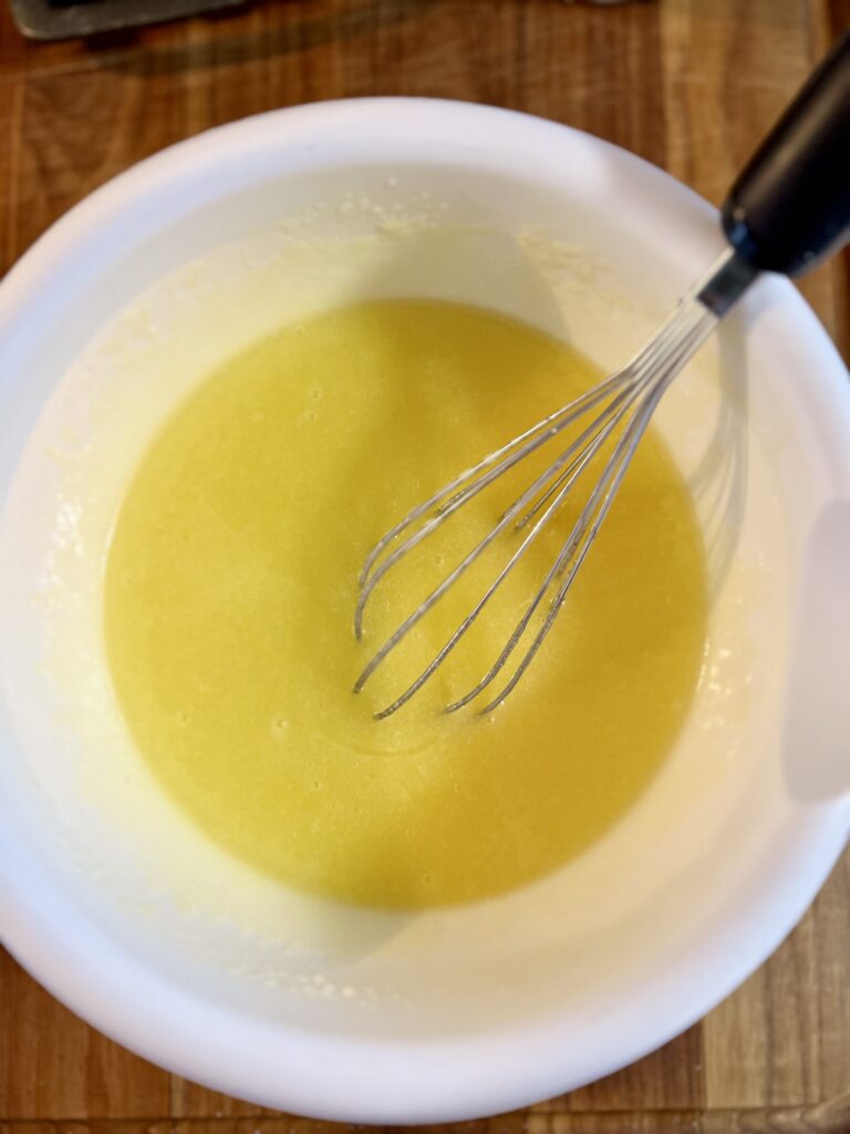 Melted butter and eggs whisked together in a white bowl for ranger cookies