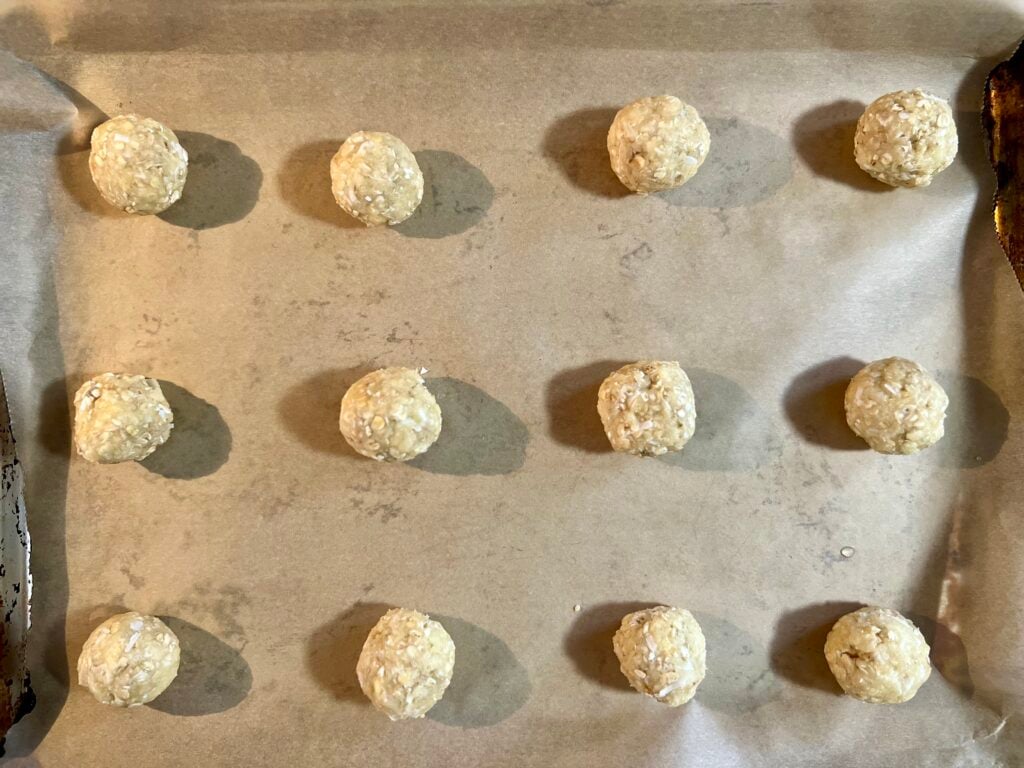 cookie dough balls evenly spaced on a parchment-lined baking sheet before baking