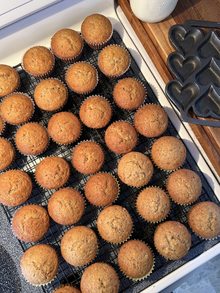 a large batch of freshly made sourdough banana muffins on a cooling rack.