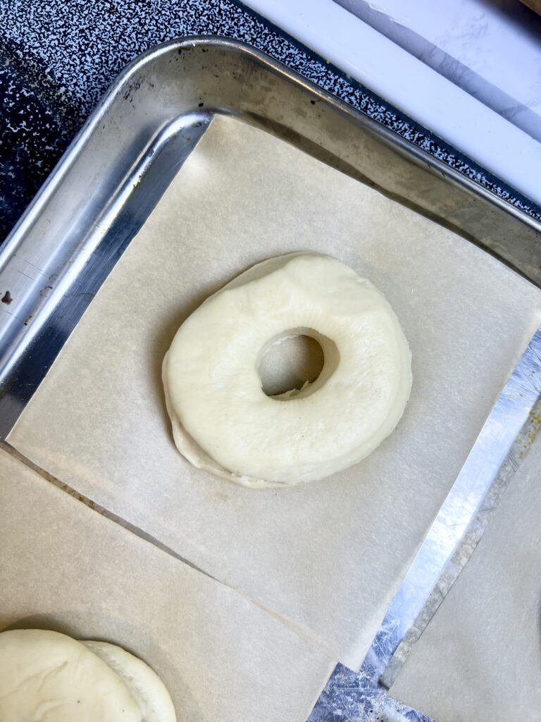 a donut but cut out and shaped and placed on a parchment lined baking sheet. Ready to be fried.