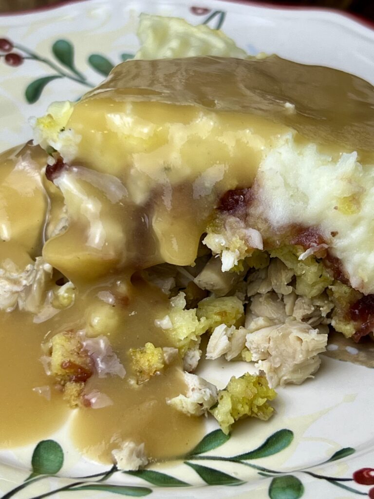 Thanksgiving leftover lasagna served with gravy, made as a layered thanksgiving casserole with turkey, stuffing, cranberry sauce, and mashed potatoes