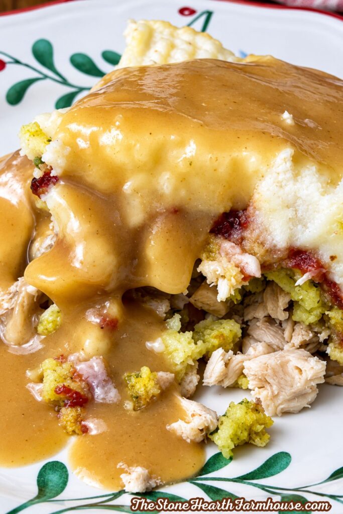 Close-up of Thanksgiving casserole layered with turkey, stuffing, mashed potatoes, cranberry sauce, and gravy