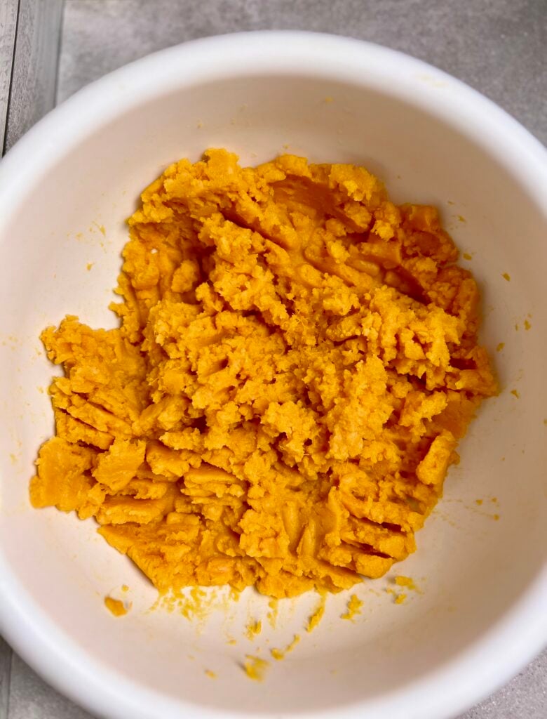 Mashed canned yams in mixing bowl prepared for Sweet Potato Casserole with Canned Yams before adding eggs, sugar, and milk.