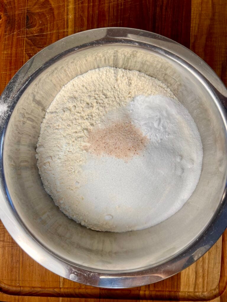 Flour, sugar, baking soda, and salt measured in mixing bowl for traditional Irish soda bread recipe.