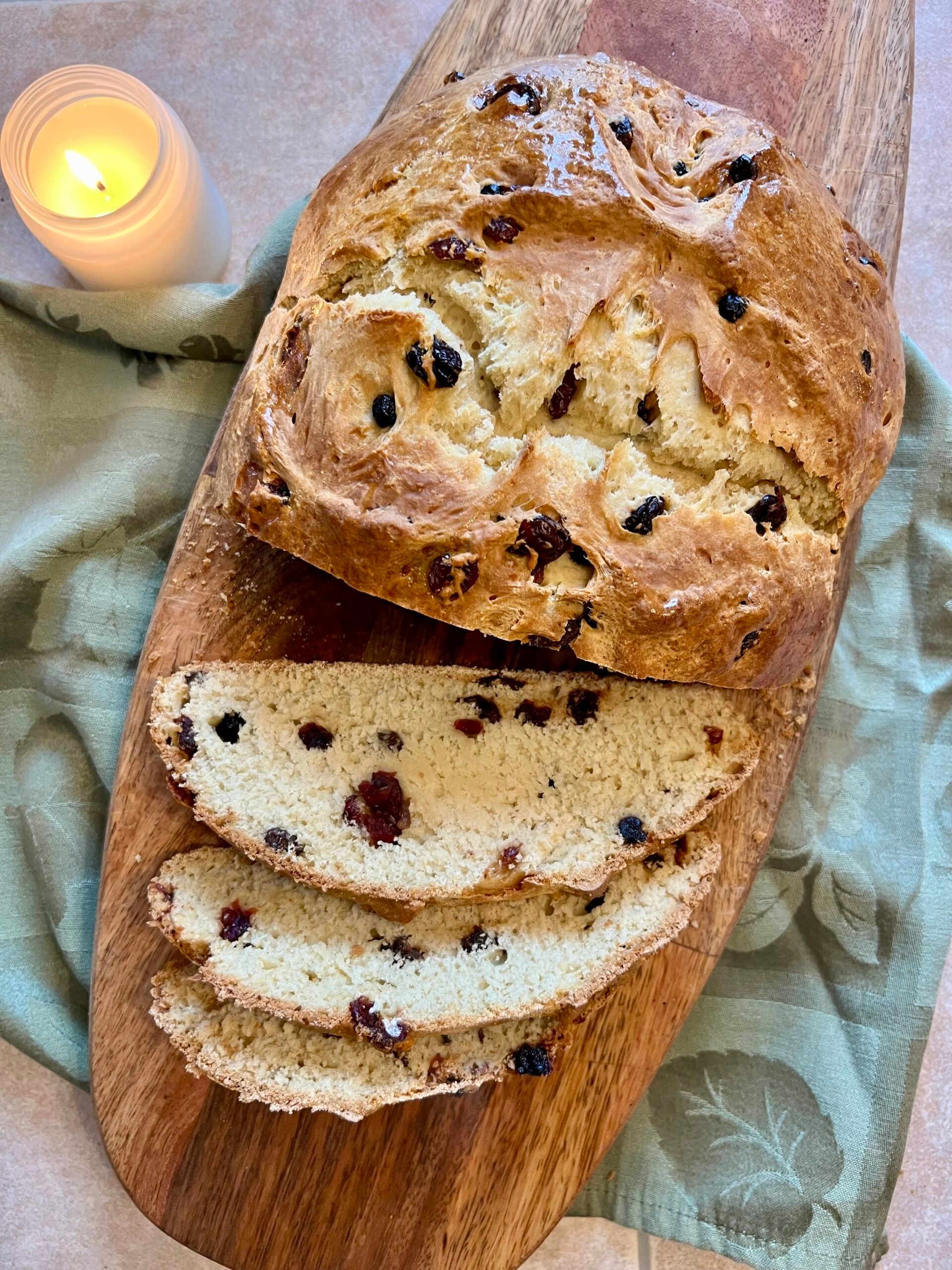 Homemade Irish soda bread loaf with traditional cross on top, sliced and served on wooden board with rustic kitchen styling.
