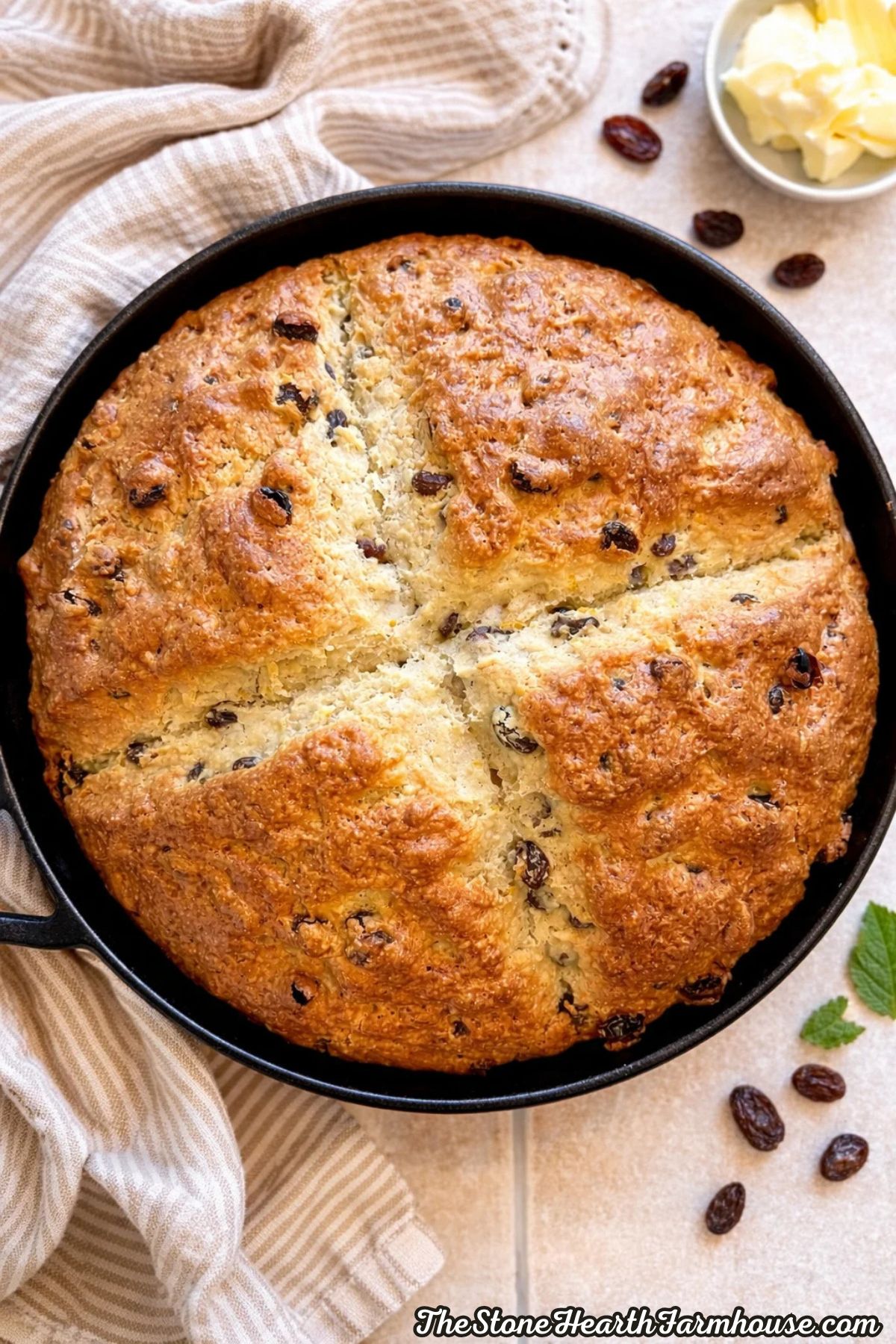 Round homemade Irish soda bread made with sourdough discard and raisins, baked until golden brown in a cast iron skillet.