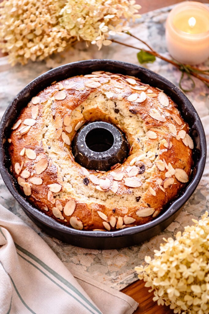 Old-fashioned babka recipe baked in a Bundt pan topped with sliced almonds and powdered sugar, golden brown sweet bread for Easter or special occasions