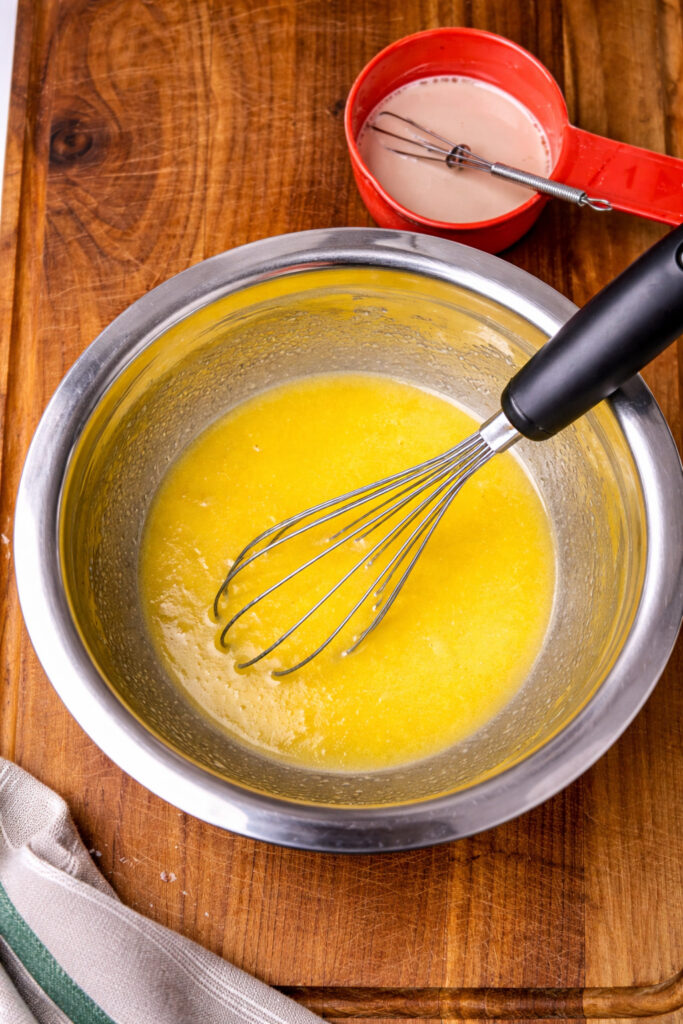 Mixing butter and yeast mixture in a bowl for homemade babka dough, step-by-step babka recipe preparation with warm ingredients