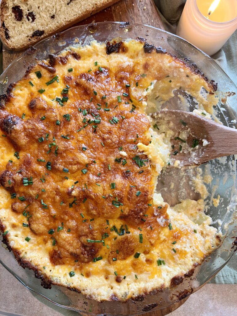 Cheddar potato gratin after serving, showing creamy layers of thinly sliced Yukon gold potatoes baked with half and half and sharp cheddar cheese.