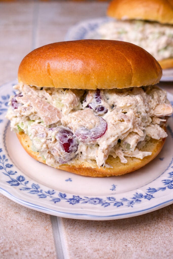 Homemade chicken salad sandwich on a soft bun filled with creamy chicken salad, grapes, and celery