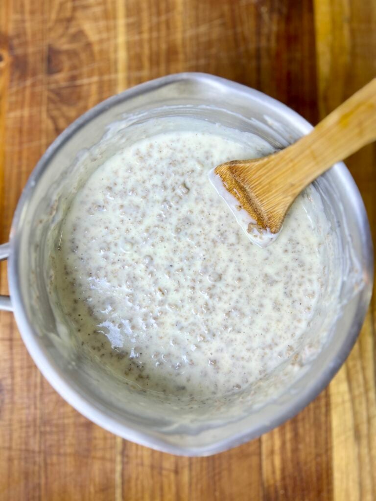 Homemade queso dip with ground beef before adding cilantro in a saucepan with a wooden spoon.