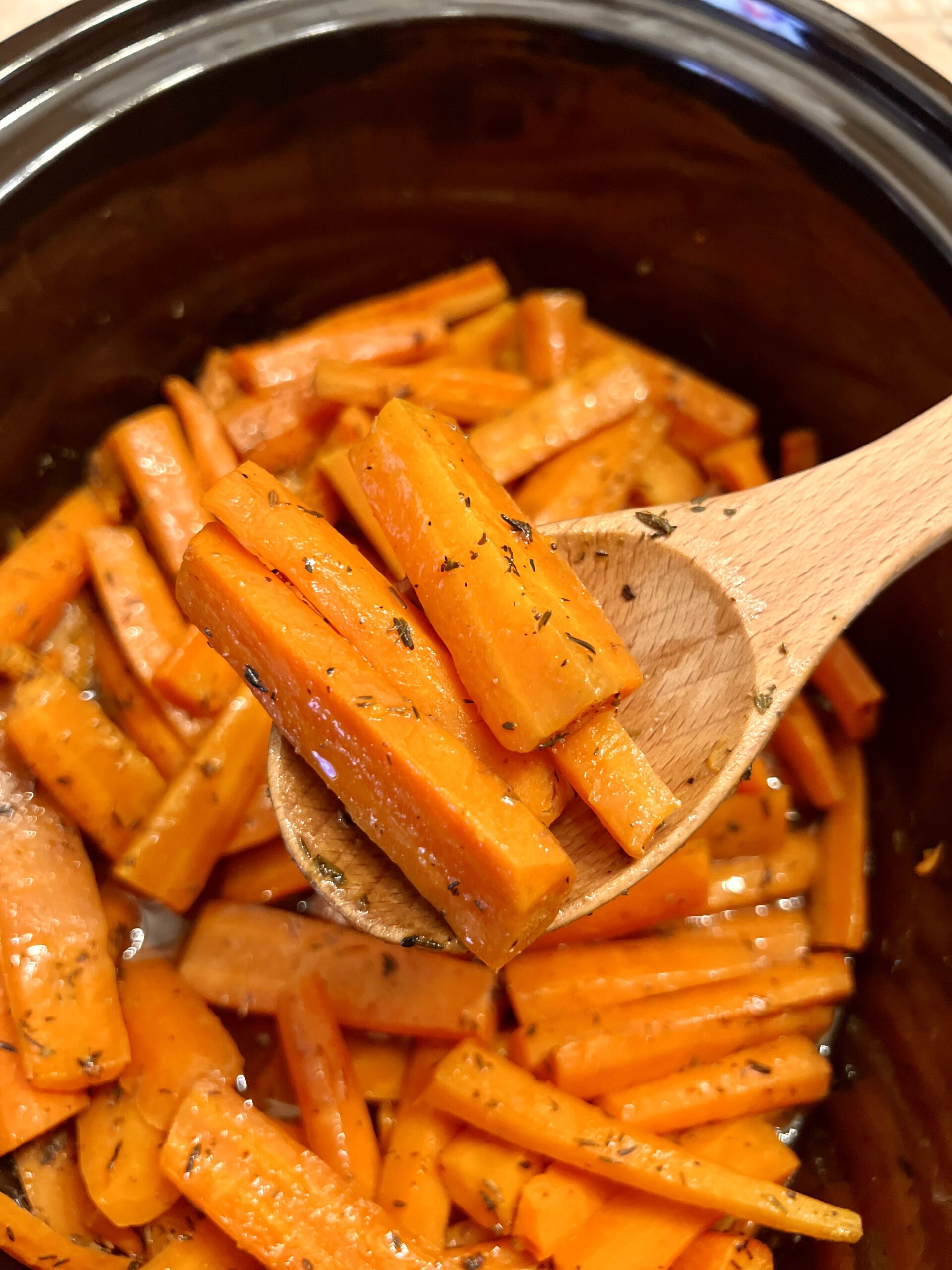 Slow cooker glazed carrots simmering in crock pot with sweet brown sugar and butter glaze, easy holiday side dish recipe.
