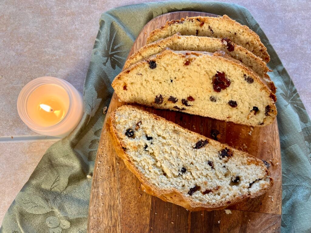 Traditional Irish soda bread with raisins and caraway seeds sliced on a wooden board, showing tender crumb and golden crust.