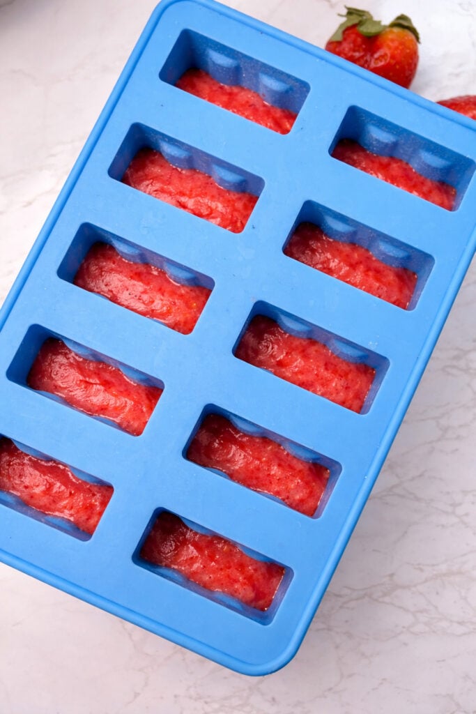 The first red strawberry layer in the popsicle molds.