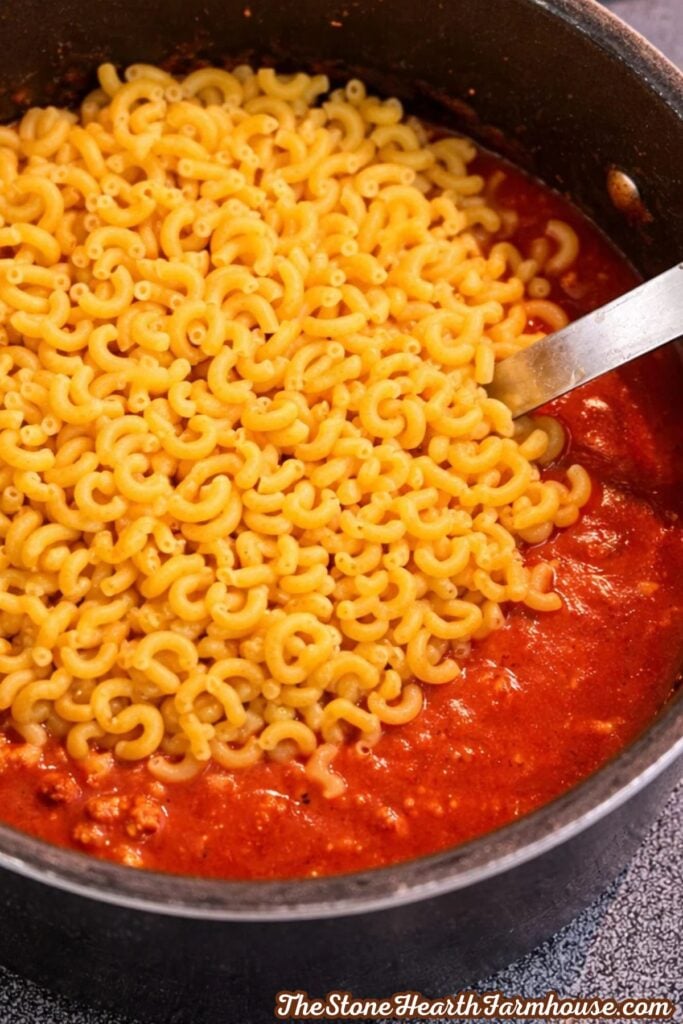 Elbow macaroni added to seasoned ground beef and tomato sauce for American chop suey