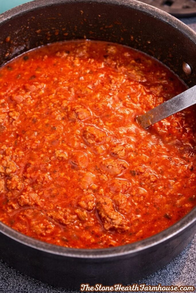 Tomato-based American chop suey sauce with seasoned ground beef simmering in a pot