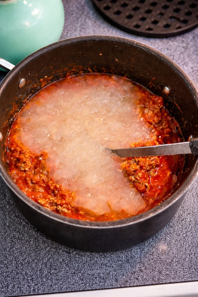American chop suey recipe beef with broth added to tomato mixture, creating a rich sauce for cooking elbow macaroni noodles