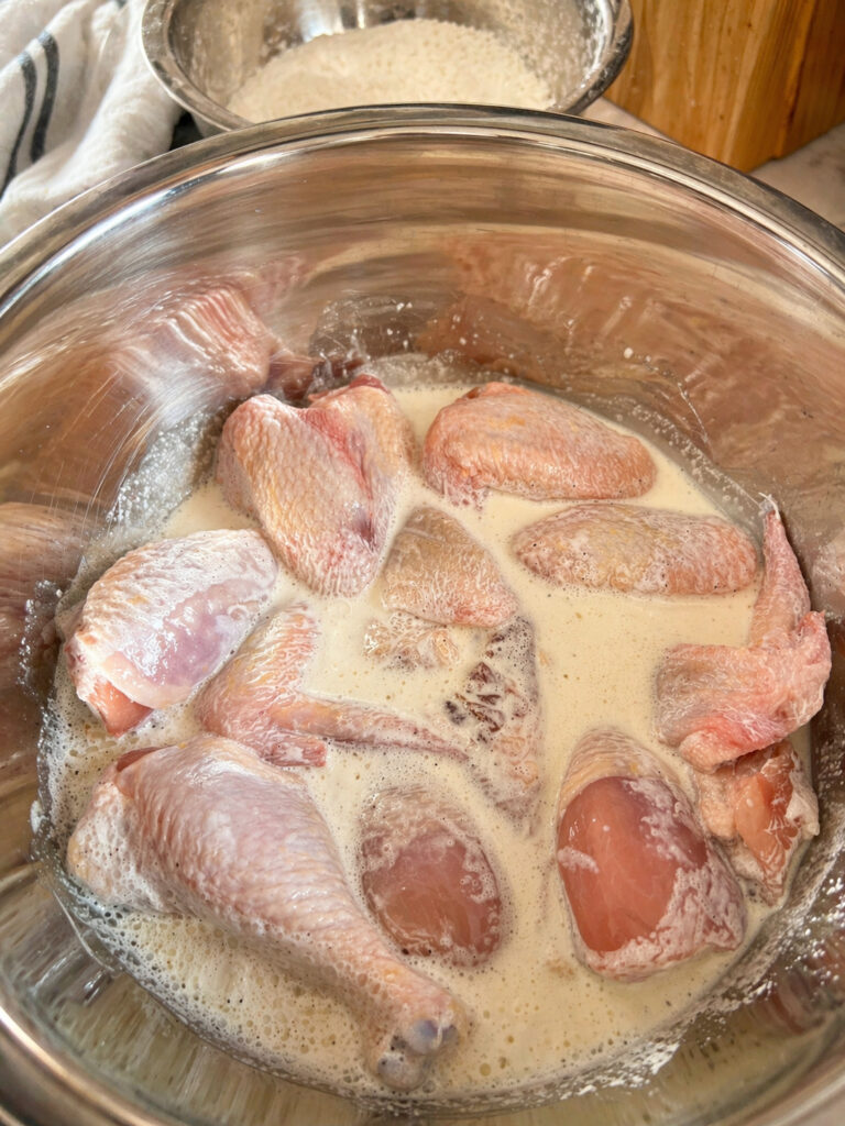 Chicken soaking in buttermilk marinade with hot sauce for juicy Bojangles chicken recipe