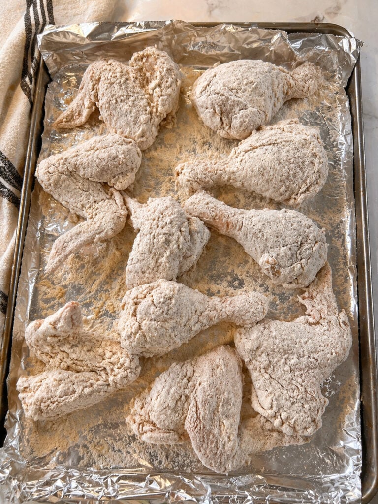 Bojangles chicken recipe raw chicken coated in seasoned flour mixture on baking sheet ready for frying