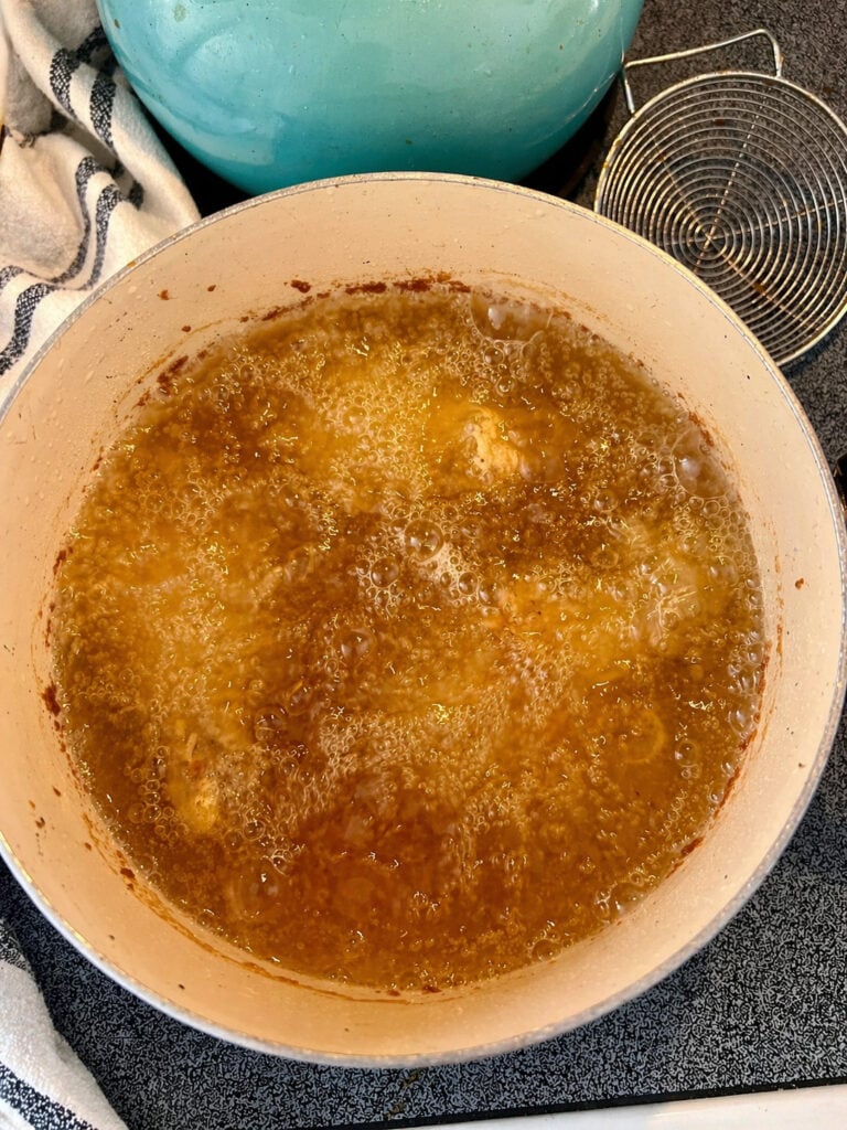 Hot peanut oil bubbling in skillet for frying Bojangles chicken recipe to golden brown perfection