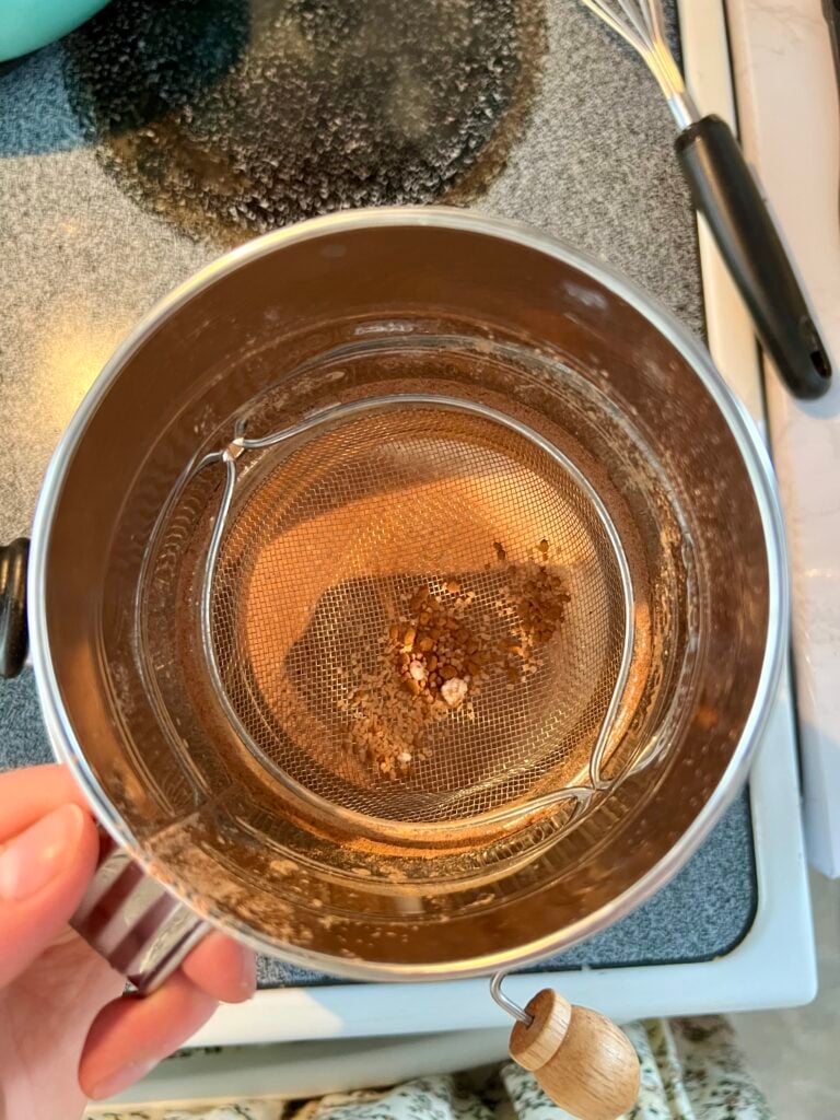 Remaining clumps after sifting cocoa powder for homemade chocolate pudding, showing how a sifter helps create a lump-free mixture