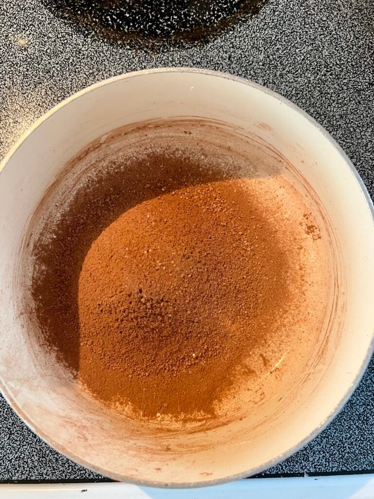 Dry ingredients for homemade chocolate pudding including cocoa powder, sugar, and cornstarch in a saucepan before mixing on the stovetop