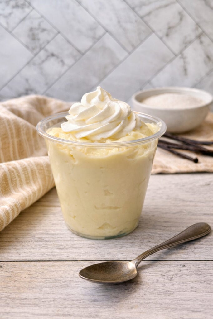 Homemade vanilla pudding in a cup topped with whipped cream, rich and creamy classic dessert made from scratch