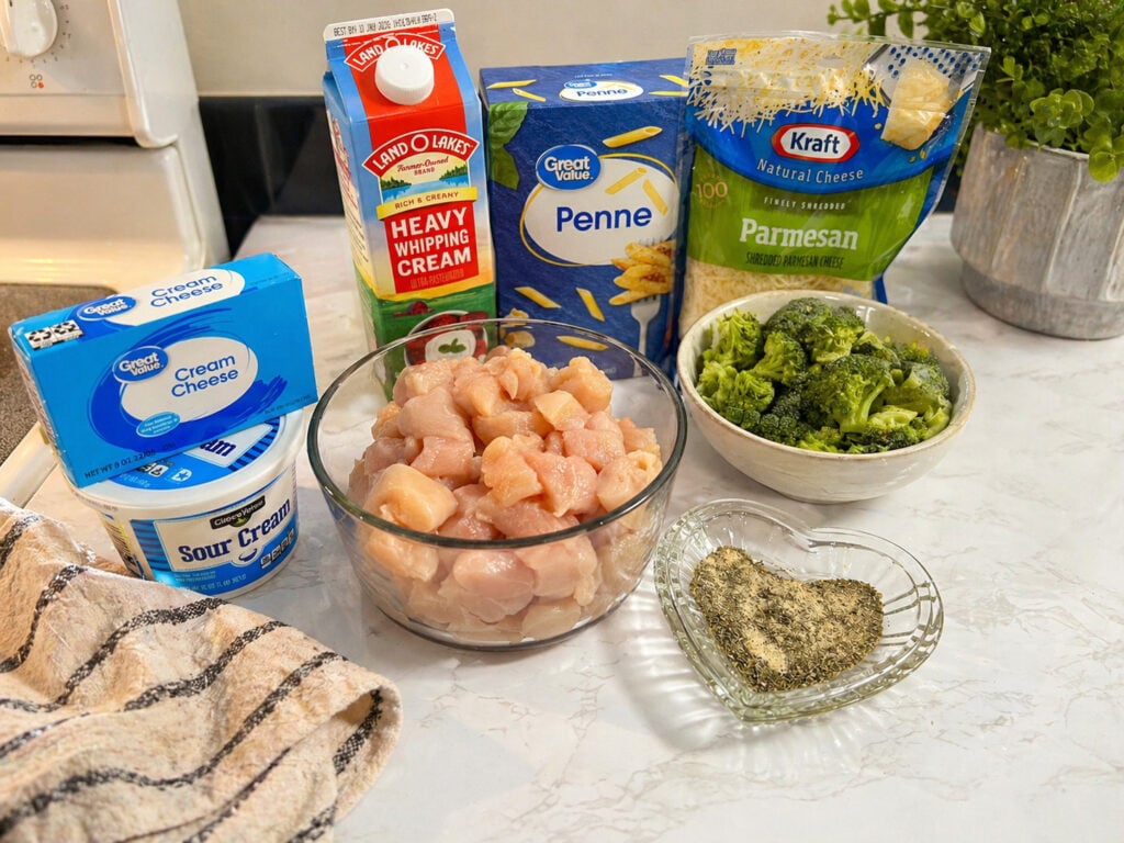 Ingredients for instant pot chicken broccoli pasta including chicken, pasta, cream, and cheese