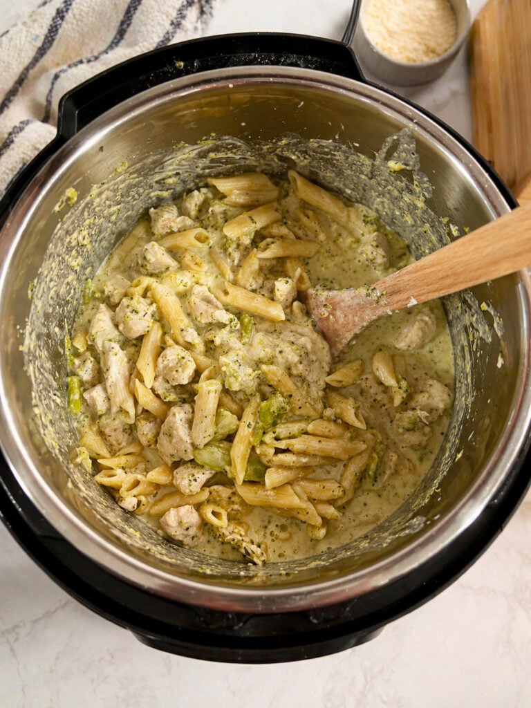 Creamy instant pot chicken broccoli pasta being stirred with sauce and penne